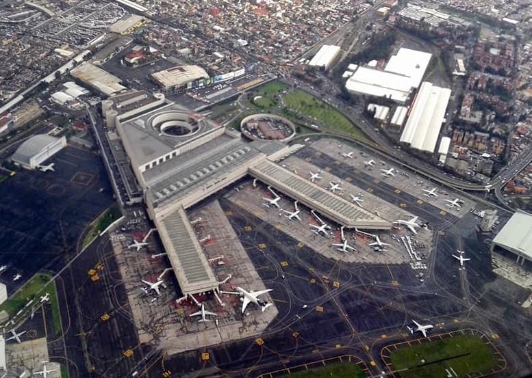 Vista aérea del Aeropuerto Internacional Benito Juárez de la Ciudad de México con terminales, pistas y aviones estacionados.