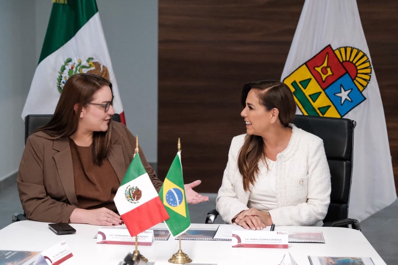 La gobernadora Mara Lezama sostiene una reunión bilateral con autoridades de Brasil, con las banderas de México y Brasil sobre la mesa, en un contexto de diálogo diplomático sobre turismo.