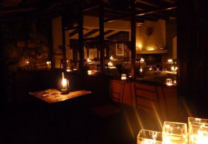 Interior de restaurante iluminado solo por velas y lámparas de emergencia durante apagón nocturno.