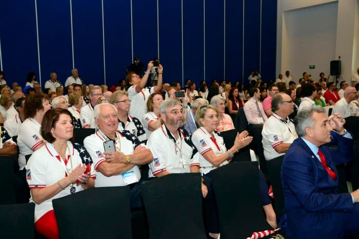 Asistentes a un evento de convenciones en Cancún, varios con credenciales y uniformes corporativos, en una sala de conferencias.