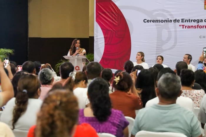 Mujer en podio dirigiéndose a audiencia durante ceremonia de entrega de transformación digital en evento oficial.